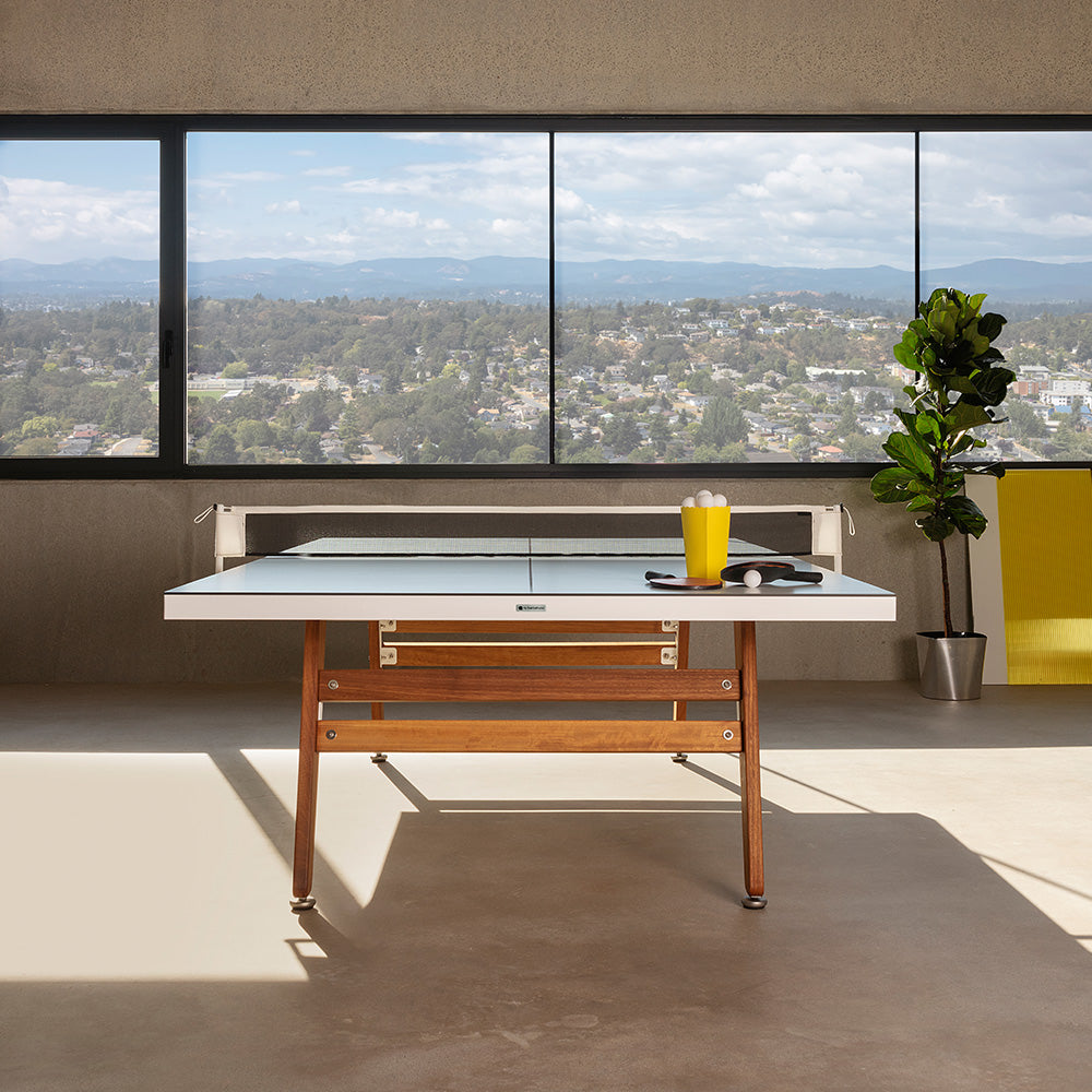 Mesa de ping pong RS Barcelona con patas de madera en ático lujoso.